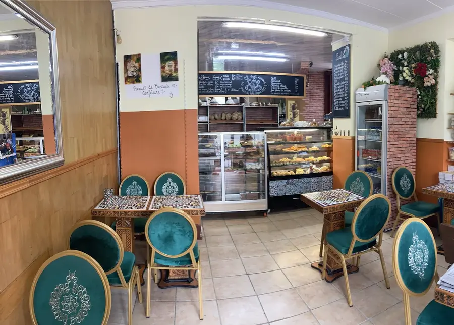 Salle intérieure : chaises en velours vert, tables en mosaïque marocaine, comptoir au fond.